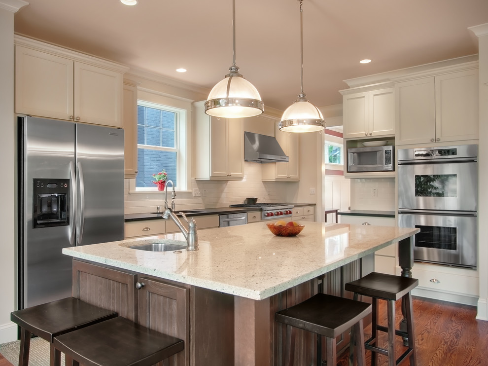 Mid-sized transitional l-shaped medium tone wood floor kitchen photo in Seattle with shaker cabinets, white cabinets, quartzite countertops, white backsplash, subway tile backsplash, stainless steel appliances and an island