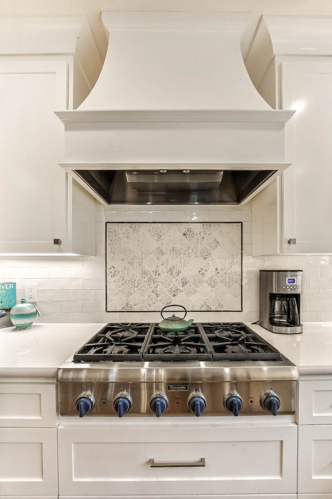 サンフランシスコにある中くらいなトランジショナルスタイルのおしゃれなキッチン (エプロンフロントシンク、シェーカースタイル扉のキャビネット、白いキャビネット、珪岩カウンター、白いキッチンパネル、サブウェイタイルのキッチンパネル、シルバーの調理設備、無垢フローリング、茶色い床、白いキッチンカウンター) の写真