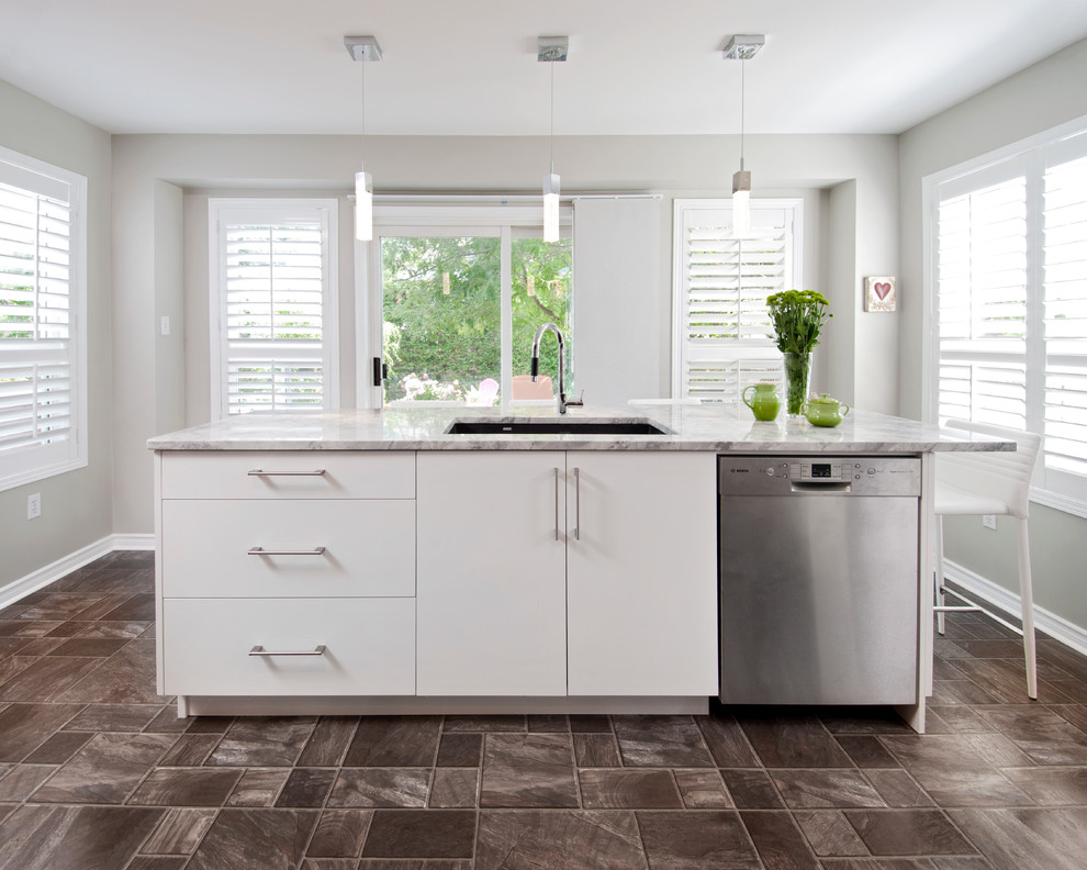 Cette photo montre une cuisine américaine tendance avec des portes de placard blanches, plan de travail en marbre et un électroménager en acier inoxydable.