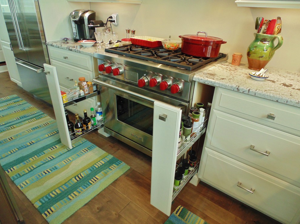 Inredning av ett klassiskt mellanstort kök, med en rustik diskho, luckor med upphöjd panel, vita skåp, granitbänkskiva, beige stänkskydd, rostfria vitvaror, mellanmörkt trägolv och en köksö