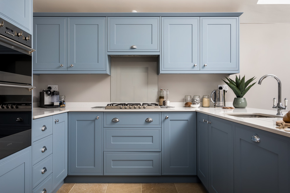 Bild på ett stort lantligt kök, med en enkel diskho, luckor med infälld panel, blå skåp, integrerade vitvaror och beiget golv