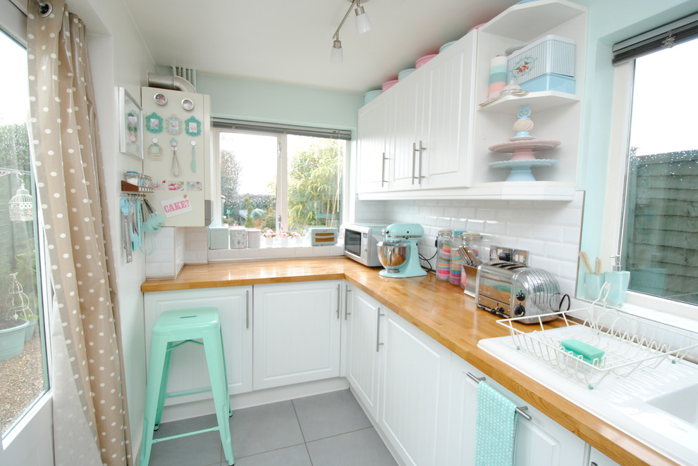 Example of a beach style kitchen design in Devon with subway tile backsplash and wood countertops