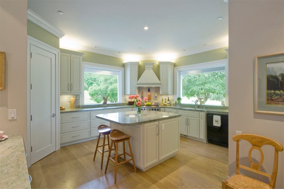 Exempel på ett avskilt, mellanstort lantligt u-kök, med en enkel diskho, luckor med profilerade fronter, vita skåp, granitbänkskiva, vitt stänkskydd, rostfria vitvaror, ljust trägolv och en köksö