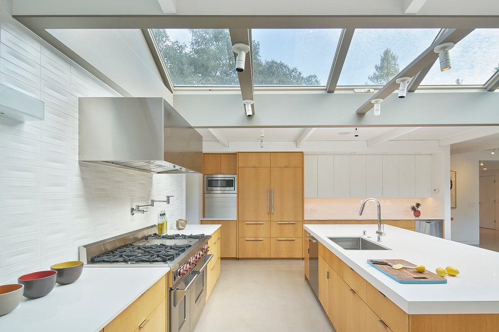 Moderne Küche mit Unterbauwaschbecken, flächenbündigen Schrankfronten, Küchenrückwand in Weiß, Küchengeräten aus Edelstahl, Betonboden, Kücheninsel und hellen Holzschränken in San Francisco