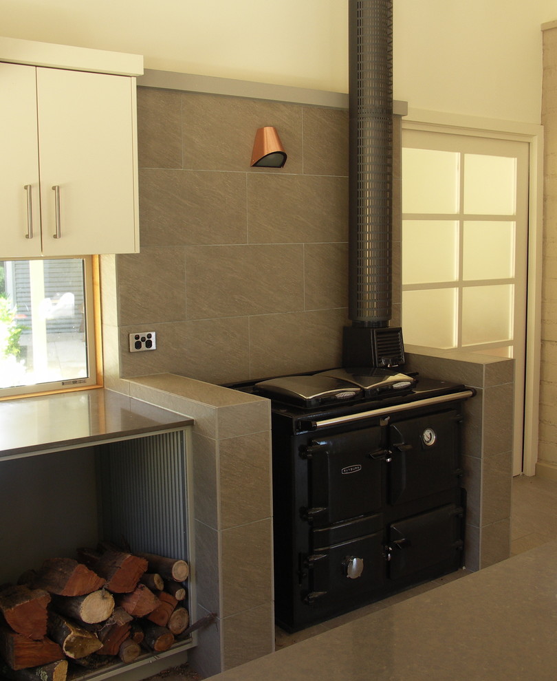 Bild på ett mellanstort funkis kök, med släta luckor, vita skåp, bänkskiva i kvarts, grått stänkskydd, stänkskydd i keramik, rostfria vitvaror, klinkergolv i porslin och en köksö