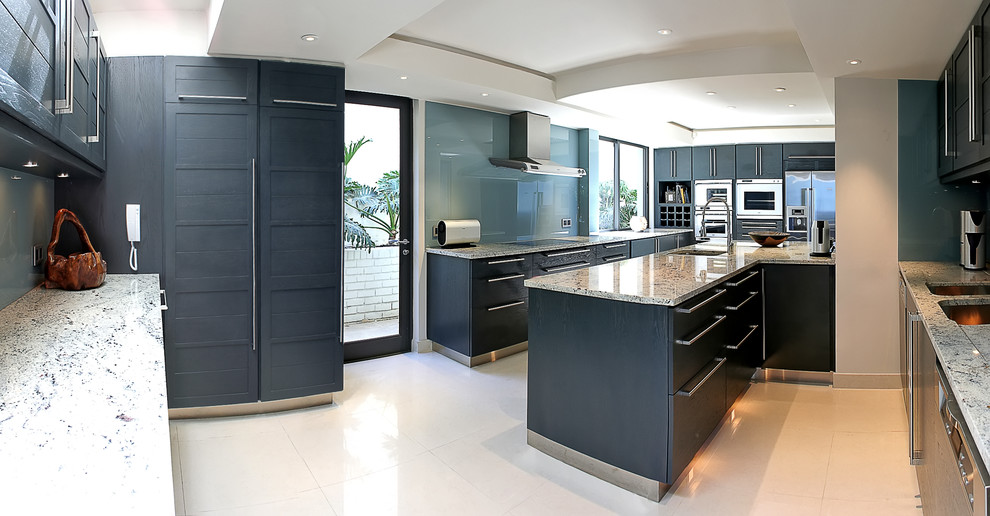 Moderne Küche mit Schrankfronten im Shaker-Stil, blauen Schränken, Granit-Arbeitsplatte, Küchenrückwand in Grau, Glasrückwand und Küchengeräten aus Edelstahl in Sonstige