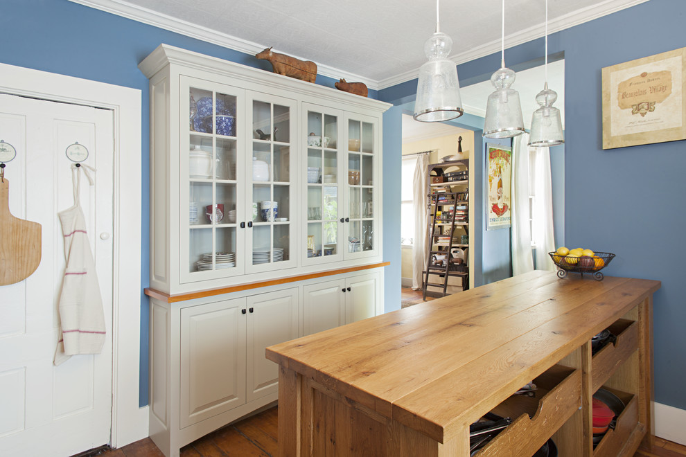 Aménagement d'une cuisine ouverte classique avec un placard à porte vitrée, des portes de placard grises et un plan de travail en bois.