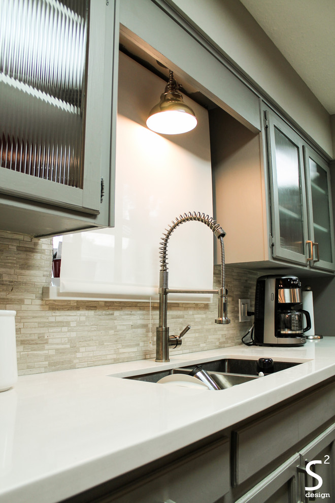 Bild på ett mellanstort 50 tals kök, med en undermonterad diskho, luckor med glaspanel, grå skåp, bänkskiva i kvartsit, grått stänkskydd, stänkskydd i stenkakel, rostfria vitvaror, klinkergolv i porslin och en halv köksö
