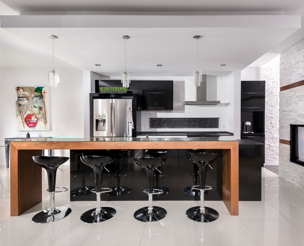 モントリオールにあるコンテンポラリースタイルのおしゃれなキッチン (フラットパネル扉のキャビネット、黒いキャビネット、木材カウンター、黒いキッチンパネル、シルバーの調理設備、白い床) の写真
