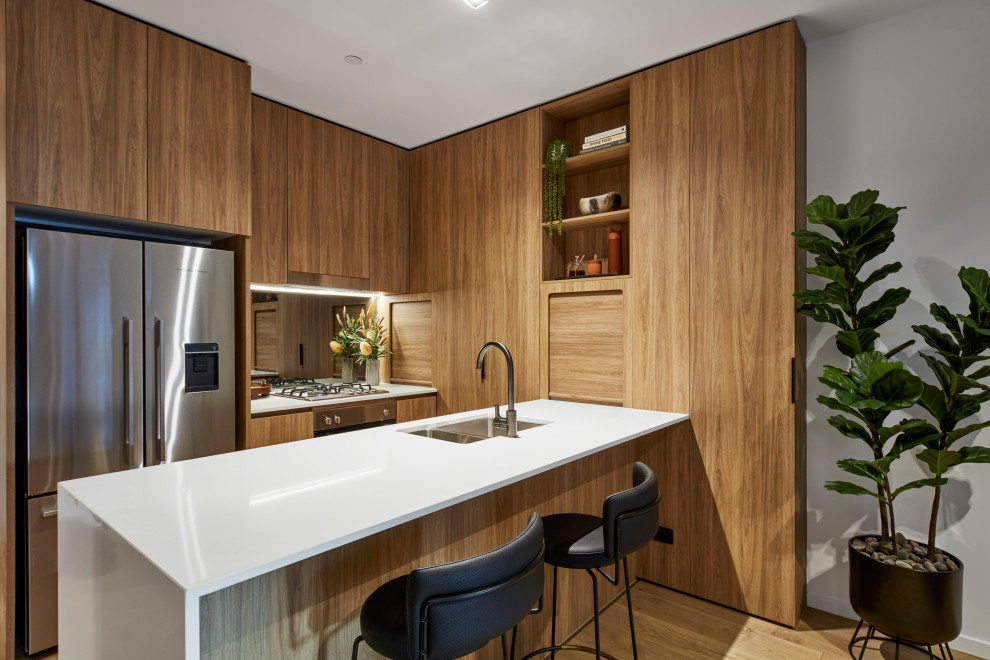 Esempio di una cucina minimal con lavello sottopiano, ante lisce, ante in legno scuro, elettrodomestici in acciaio inossidabile, pavimento in legno massello medio, pavimento marrone e top bianco