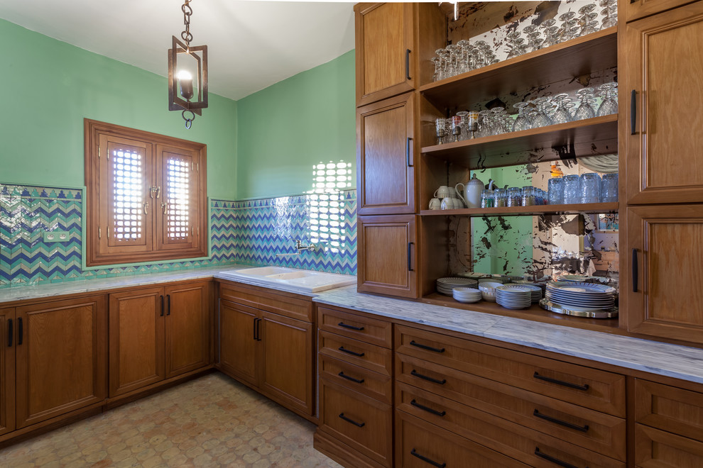 Example of a tuscan l-shaped terra-cotta tile eat-in kitchen design in Chicago with a drop-in sink, shaker cabinets, dark wood cabinets, blue backsplash, porcelain backsplash, paneled appliances, a peninsula and gray countertops