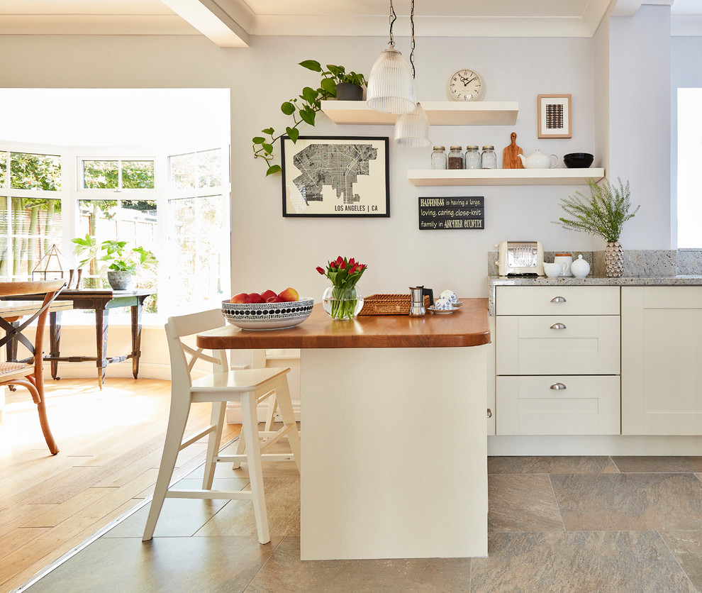 Foto på ett mellanstort vintage grå kök och matrum, med skåp i shakerstil, granitbänkskiva, grått stänkskydd, stänkskydd i sten, klinkergolv i keramik, beige skåp, en halv köksö och beiget golv