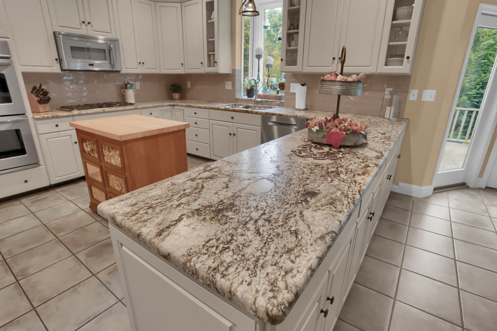 Example of a mid-sized classic u-shaped ceramic tile and beige floor eat-in kitchen design in Other with a double-bowl sink, raised-panel cabinets, white cabinets, granite countertops, beige backsplash, ceramic backsplash, stainless steel appliances, an island and white countertops
