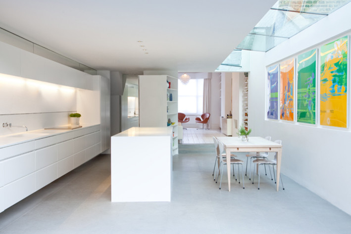 Ejemplo de cocina comedor lineal actual de tamaño medio con puertas de armario blancas y suelo de cemento