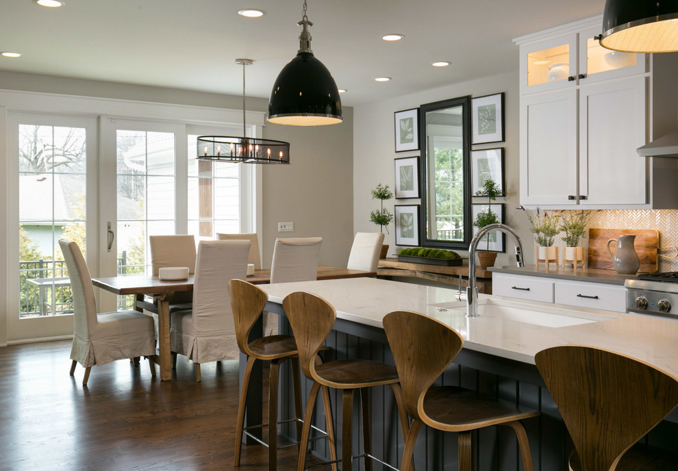 Example of a large transitional l-shaped medium tone wood floor and brown floor open concept kitchen design in Kansas City with a drop-in sink, shaker cabinets, white cabinets, quartzite countertops, white backsplash, marble backsplash, stainless steel appliances, an island and white countertops