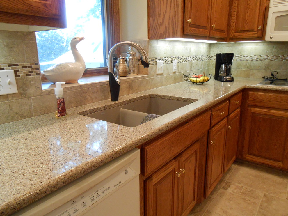 Photo of a large classic u-shaped kitchen/diner in Omaha with a submerged sink, raised-panel cabinets, medium wood cabinets, engineered stone countertops, beige splashback, porcelain splashback, white appliances, porcelain flooring and a breakfast bar.