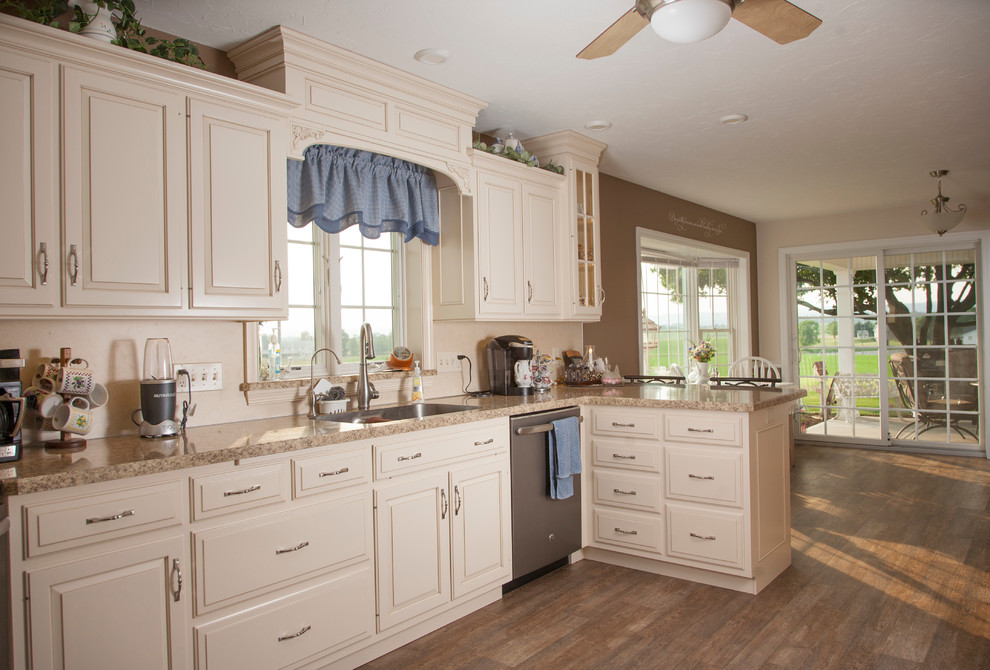 Example of a mid-sized cottage u-shaped vinyl floor eat-in kitchen design in Philadelphia with an undermount sink, raised-panel cabinets, distressed cabinets, laminate countertops, beige backsplash, stainless steel appliances and no island
