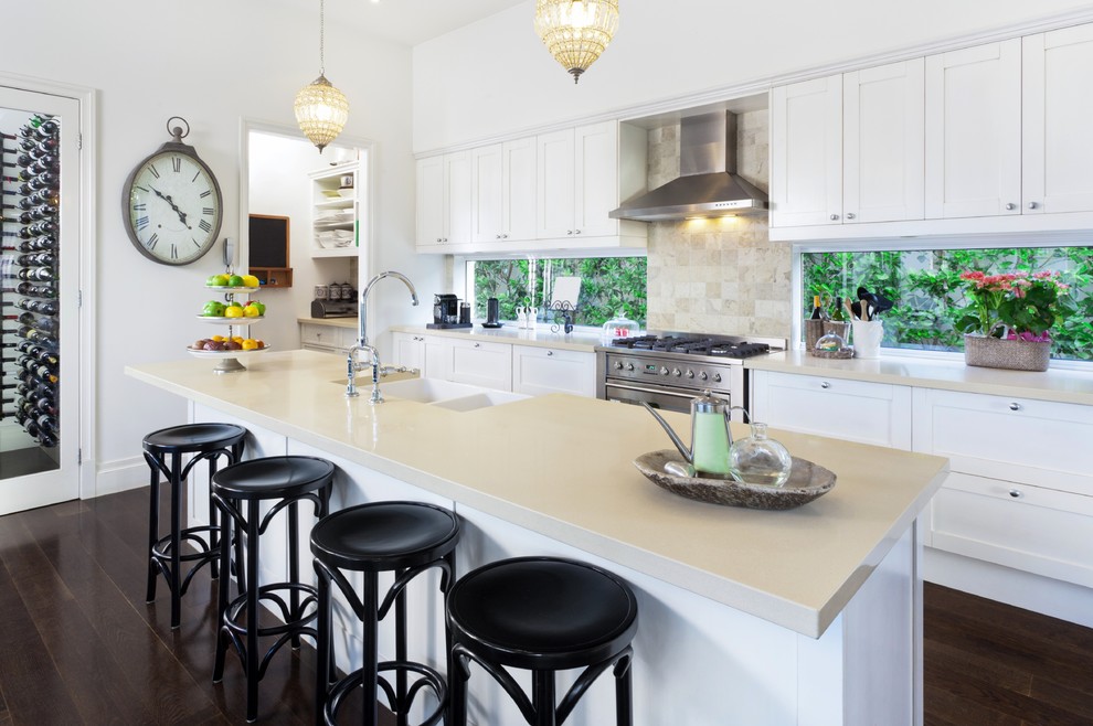 Design ideas for a large traditional galley kitchen/diner in Salt Lake City with a belfast sink, shaker cabinets, white cabinets, engineered stone countertops, window splashback, stainless steel appliances, dark hardwood flooring, an island and brown floors.