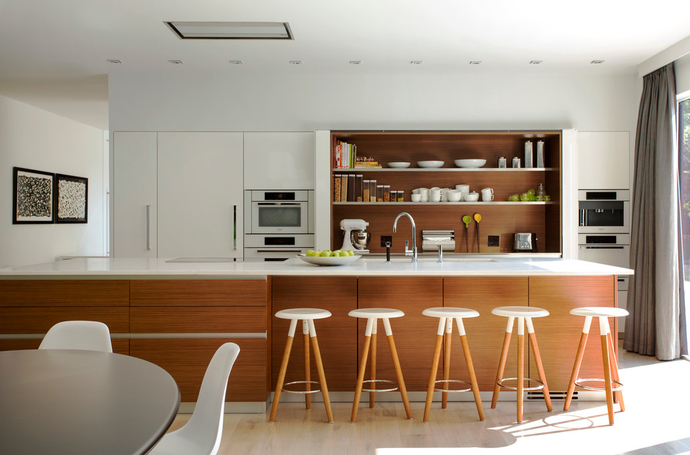 Cette photo montre une cuisine ouverte linéaire tendance avec un placard à porte plane, des portes de placard blanches, une crédence blanche, un électroménager blanc, parquet clair et îlot.