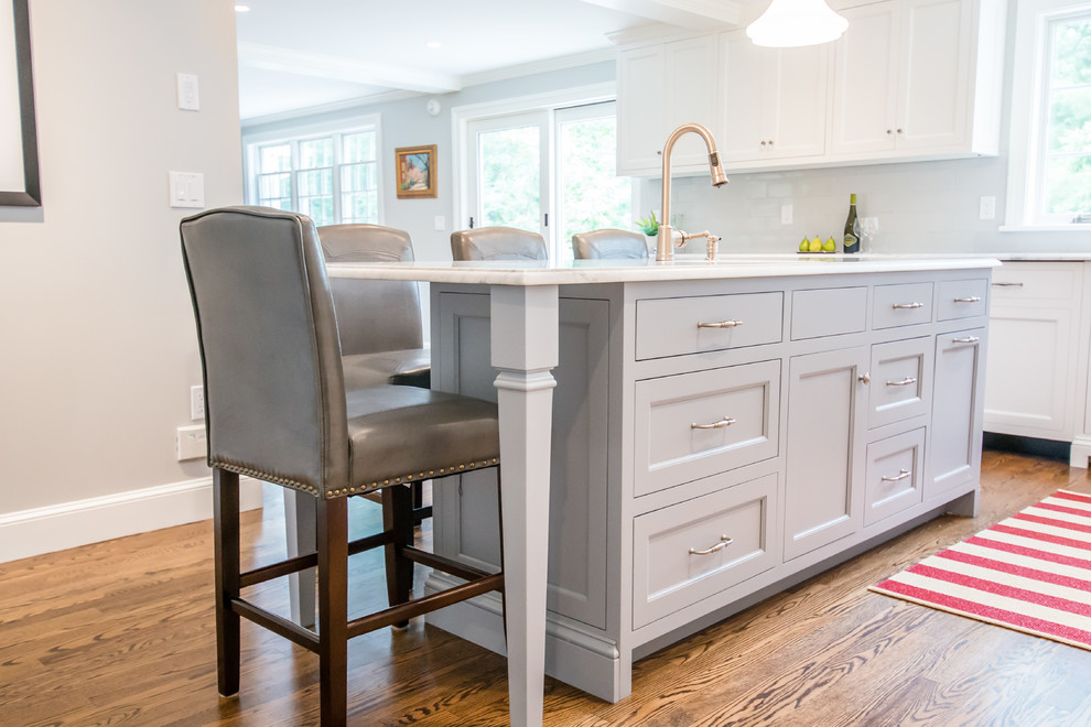 Large transitional l-shaped light wood floor eat-in kitchen photo in Portland Maine with an undermount sink, shaker cabinets, white cabinets, white backsplash, stainless steel appliances, an island, marble countertops and subway tile backsplash