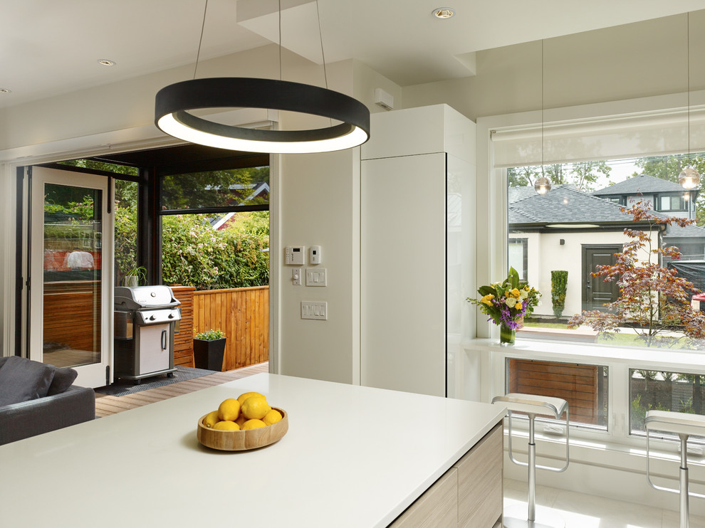 Kitchen - contemporary u-shaped ceramic tile kitchen idea in Vancouver with an undermount sink, flat-panel cabinets, quartz countertops, white backsplash, glass tile backsplash, paneled appliances and an island