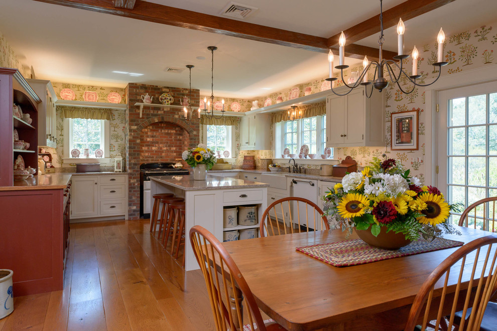 Eat-in kitchen - large cottage u-shaped medium tone wood floor eat-in kitchen idea in Manchester with a farmhouse sink, recessed-panel cabinets, white cabinets, granite countertops, white appliances and an island
