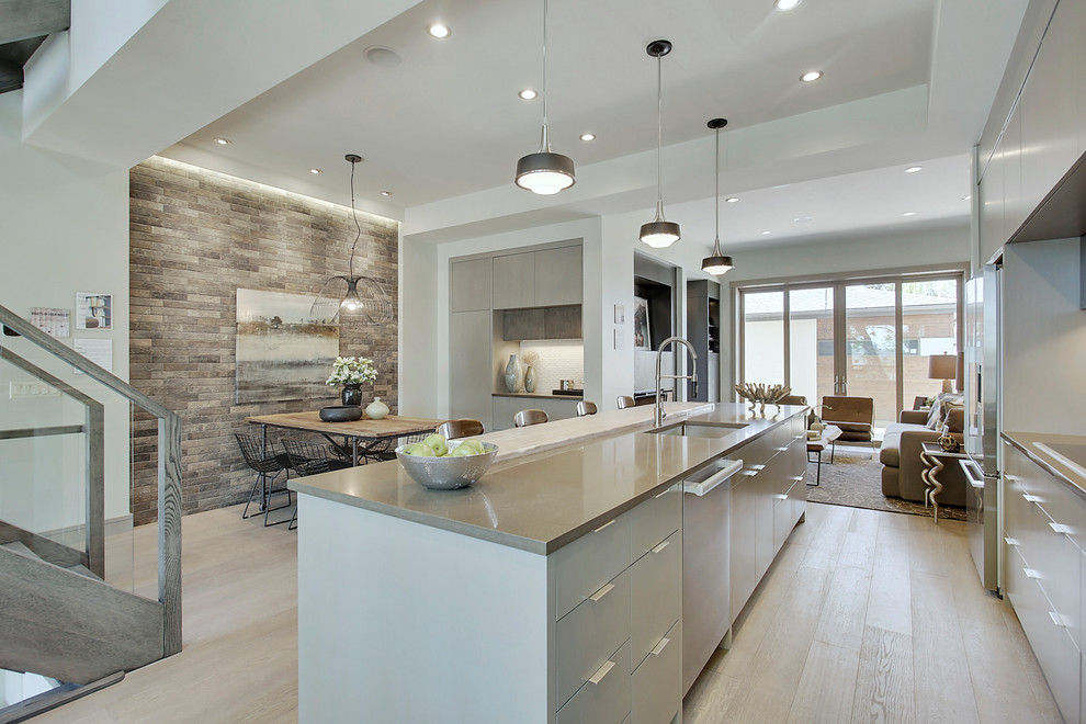 Photo of a medium sized contemporary single-wall open plan kitchen in Calgary with a single-bowl sink, flat-panel cabinets, grey cabinets, engineered stone countertops, white splashback, mosaic tiled splashback, stainless steel appliances, medium hardwood flooring, an island and grey floors.