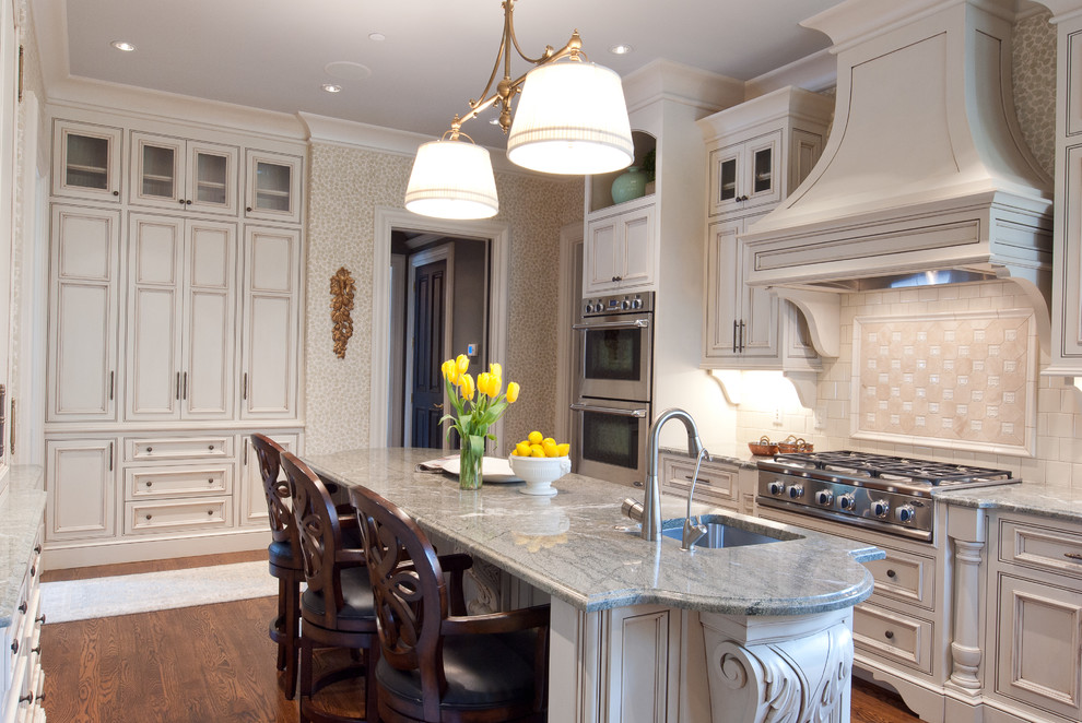 Foto på ett avskilt vintage grå kök, med marmorbänkskiva, luckor med profilerade fronter, beige skåp, en köksö, vitt stänkskydd, rostfria vitvaror och brunt golv