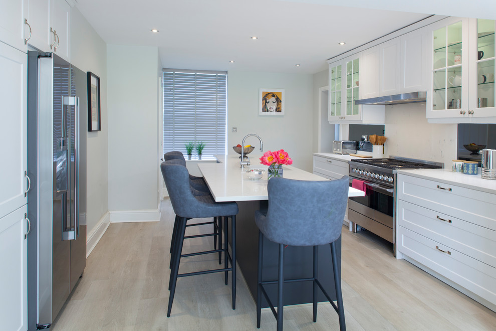 This is an example of a medium sized classic galley kitchen/diner in Other with an integrated sink, glass-front cabinets, white cabinets, quartz worktops, stainless steel appliances, medium hardwood flooring, an island, beige floors and white worktops.