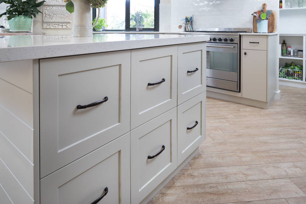 Photo of a traditional kitchen in Perth with shaker cabinets, beige cabinets, engineered stone countertops, white splashback, metro tiled splashback, stainless steel appliances, an island and white worktops.