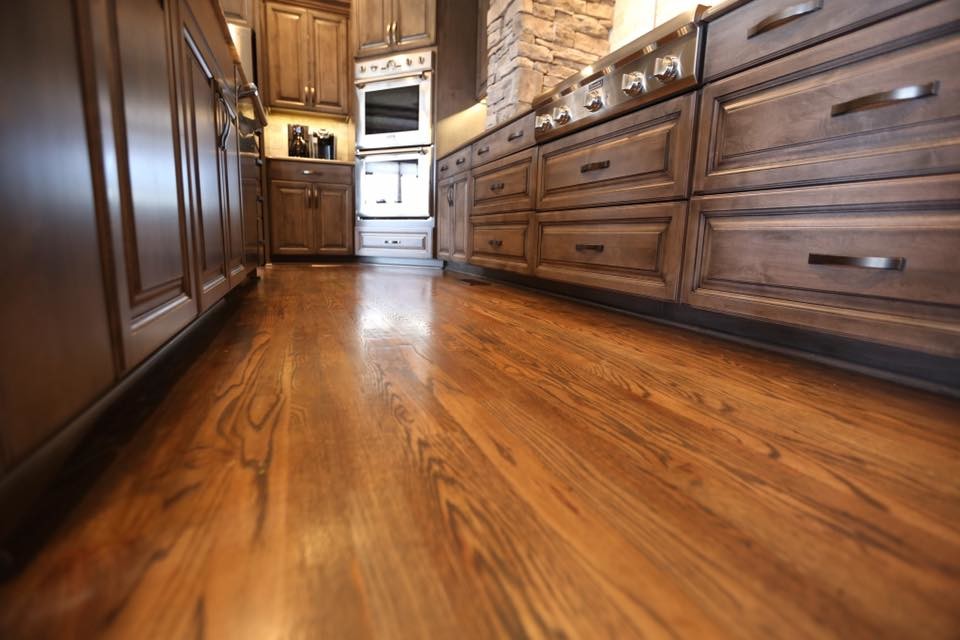 Inspiration for a large rustic u-shaped dark wood floor and brown floor eat-in kitchen remodel in Kansas City with a single-bowl sink, raised-panel cabinets, gray cabinets, granite countertops, brown backsplash, travertine backsplash, stainless steel appliances, an island and brown countertops