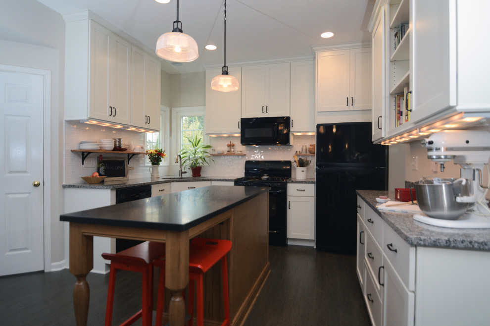 This is an example of a traditional kitchen in DC Metro with shaker cabinets, white cabinets, granite worktops, white splashback, ceramic splashback and black appliances.