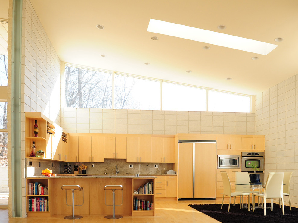 На фото: угловая кухня среднего размера в стиле модернизм с техникой под мебельный фасад, гранитной столешницей, обеденным столом, плоскими фасадами, светлыми деревянными фасадами, фартуком из каменной плиты, светлым паркетным полом и коричневым полом