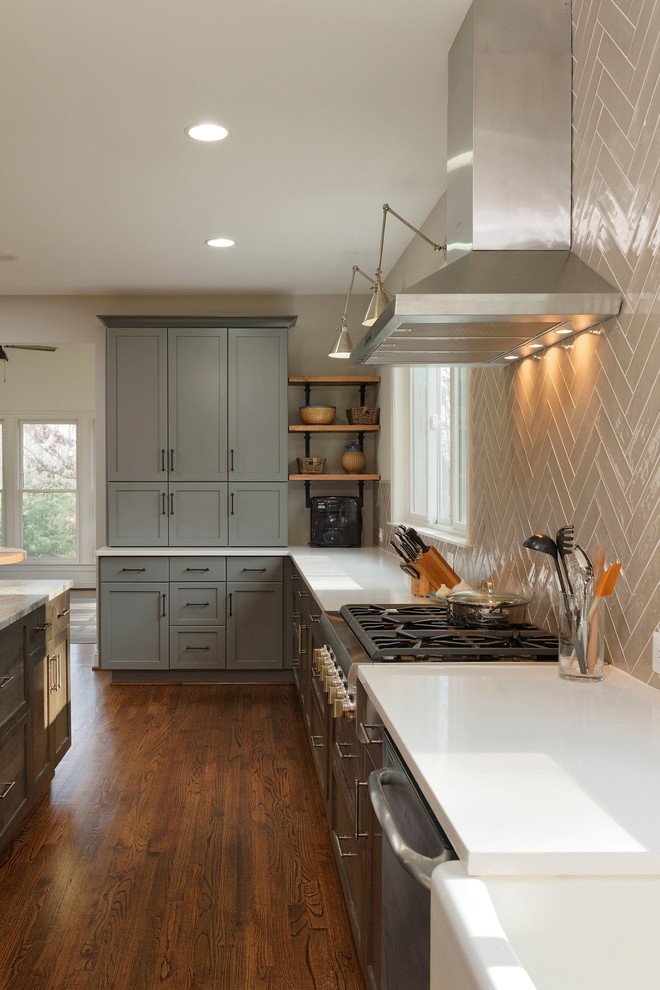 Design ideas for a large classic u-shaped kitchen/diner in DC Metro with a belfast sink, shaker cabinets, medium wood cabinets, engineered stone countertops, beige splashback, metro tiled splashback, stainless steel appliances, light hardwood flooring and an island.