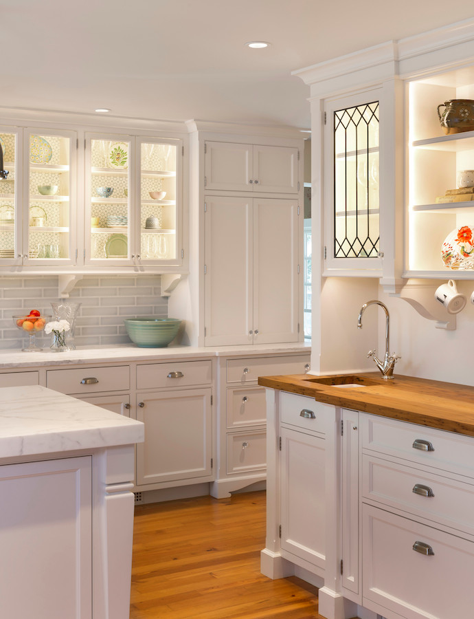 Enclosed kitchen - large cottage l-shaped dark wood floor and brown floor enclosed kitchen idea in DC Metro with a farmhouse sink, recessed-panel cabinets, white cabinets, marble countertops, gray backsplash, glass tile backsplash, stainless steel appliances and an island