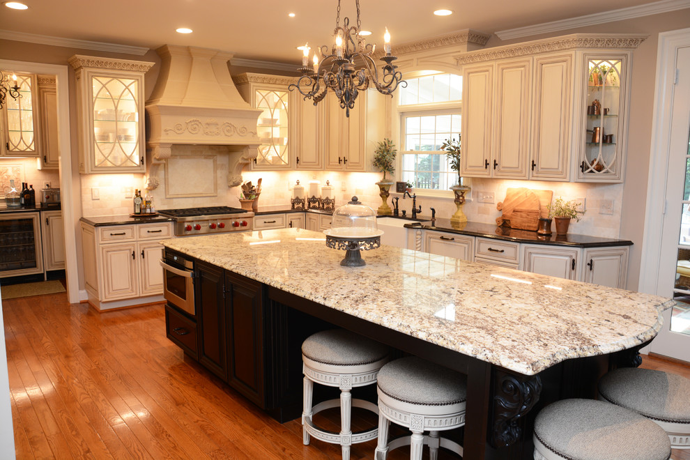 Exempel på ett stort klassiskt kök, med en rustik diskho, luckor med upphöjd panel, beige skåp, granitbänkskiva, beige stänkskydd, rostfria vitvaror, mellanmörkt trägolv, en köksö och brunt golv