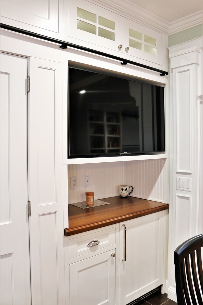 Exemple d'une grande cuisine américaine encastrable chic en L avec un placard à porte affleurante, des portes de placard blanches, une crédence blanche, un sol en carrelage de porcelaine, un sol marron et un plan de travail en bois.