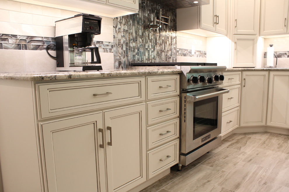Inspiration for a large contemporary l-shaped slate floor eat-in kitchen remodel in Philadelphia with a farmhouse sink, recessed-panel cabinets, distressed cabinets, granite countertops, white backsplash, subway tile backsplash, stainless steel appliances and an island