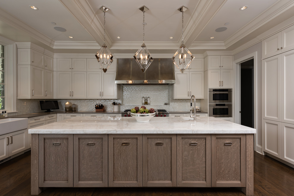 Inspiration for a large timeless u-shaped medium tone wood floor and brown floor open concept kitchen remodel in Chicago with a farmhouse sink, beaded inset cabinets, white cabinets, granite countertops, white backsplash, mosaic tile backsplash, stainless steel appliances, an island and beige countertops