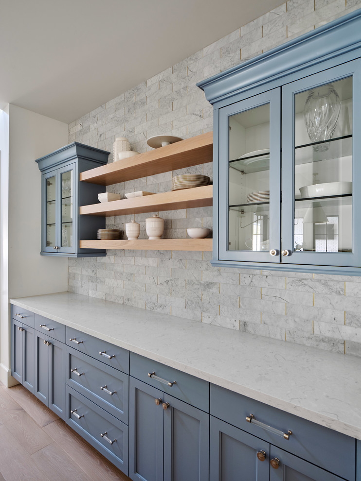 Large farmhouse open plan kitchen in Phoenix with a belfast sink, white cabinets, engineered stone countertops, grey splashback, marble splashback, integrated appliances, light hardwood flooring, an island, beige floors, grey worktops and shaker cabinets.