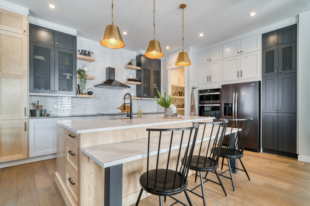Kitchen - transitional l-shaped medium tone wood floor and brown floor kitchen idea in Calgary with a farmhouse sink, shaker cabinets, gray cabinets, white backsplash, stainless steel appliances, an island and white countertops