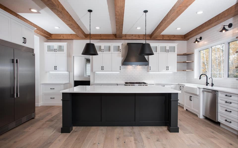 Inspiration for a large country u-shaped light wood floor and brown floor eat-in kitchen remodel in Edmonton with a farmhouse sink, shaker cabinets, black cabinets, quartz countertops, white backsplash, ceramic backsplash, stainless steel appliances, an island and white countertops