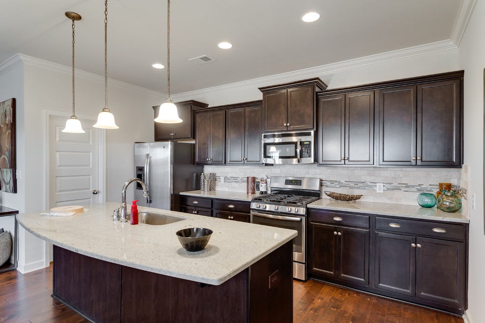 Moderne Küche mit Unterbauwaschbecken, flächenbündigen Schrankfronten, schwarzen Schränken, Granit-Arbeitsplatte, Küchengeräten aus Edelstahl und braunem Holzboden in Sonstige