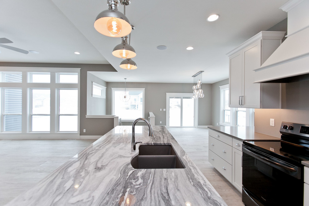 Inspiration for a large traditional single-wall open plan kitchen in Cedar Rapids with a submerged sink, shaker cabinets, white cabinets, marble worktops, stainless steel appliances, light hardwood flooring, an island and grey floors.