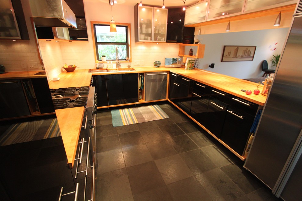 Exempel på ett mellanstort modernt kök, med släta luckor, svarta skåp, träbänkskiva, vitt stänkskydd, stänkskydd i keramik, rostfria vitvaror, en dubbel diskho och skiffergolv