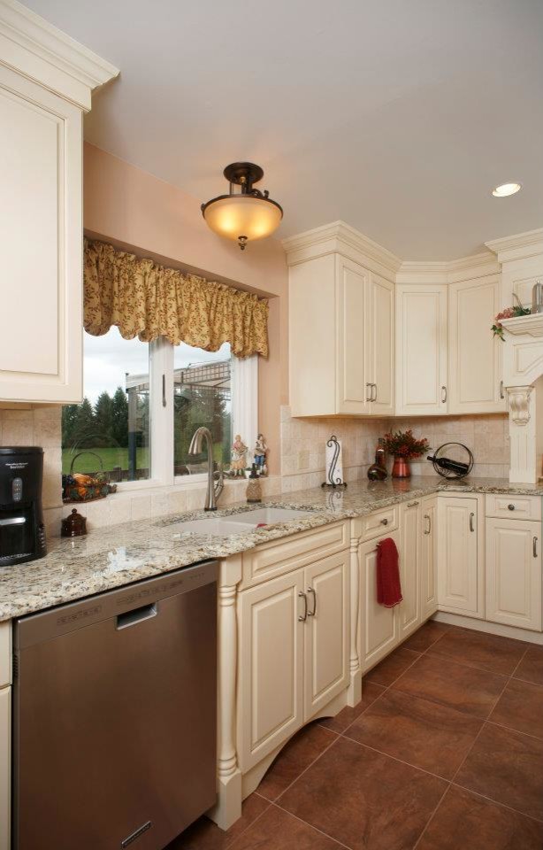 Inredning av ett klassiskt mellanstort kök, med en dubbel diskho, vita skåp, granitbänkskiva, rostfria vitvaror, luckor med upphöjd panel, beige stänkskydd, stänkskydd i stenkakel, klinkergolv i keramik och en köksö