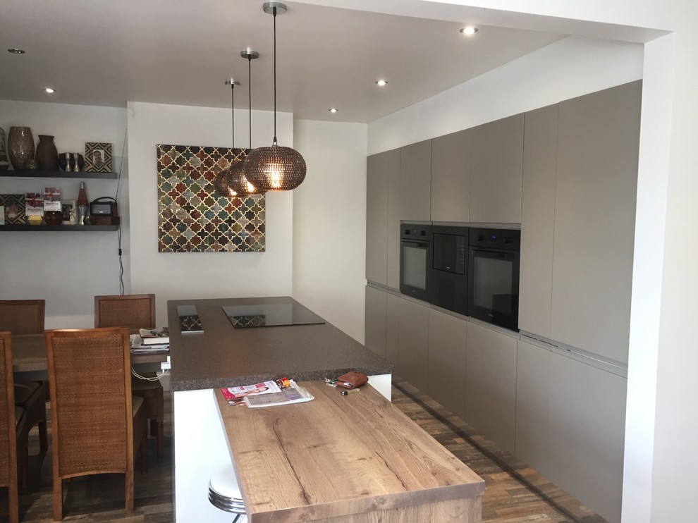 Photo of a medium sized contemporary single-wall kitchen/diner in Other with a submerged sink, flat-panel cabinets, brown cabinets, wood worktops, black appliances, vinyl flooring, an island, brown floors and multicoloured worktops.