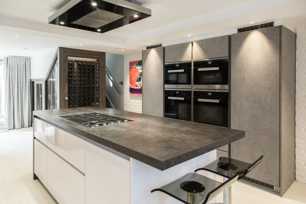 Foto på ett mellanstort funkis grå kök, med släta luckor, grå skåp, integrerade vitvaror, en köksö och beiget golv