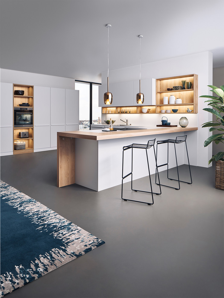 Inspiration for a medium sized modern u-shaped kitchen in New York with flat-panel cabinets, white cabinets, wood worktops and a breakfast bar.