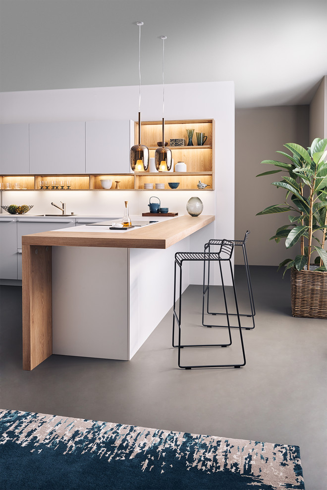 Immagine di una cucina a L minimalista di medie dimensioni con ante lisce, ante bianche, top in legno e penisola